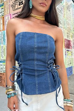 Elevate your style with our Denim Bustier Top - the ultimate addition to any wardrobe. Made of high-quality medium wash denim, this top boasts a strapless design and adjustable tie details on the sides for a personalized fit. Perfect for any occasion, whether you're having a night out, attending a country concert, or simply running errands. This versatile top is the perfect transition piece for all seasons. 70% Cotton, 28% Polyester, 2% Spandex denim strapless corset top adjustable tie side deta Fitted Denim Bandeau Top, Casual Denim Blue Bandeau Tube Top, Dark Wash Fitted Strapless Top, Denim Blue Bandeau Tube Top, Denim Blue Bandeau Tube Top For Summer, Summer Denim Blue Bandeau Tube Top, Fitted Dark Wash Strapless Top, Chic Denim Bandeau Tube Top, Strapless Denim Tube Top In Medium Wash