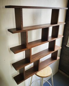 a wooden shelf sitting on top of a white wall next to a stool and window