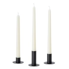 three white candles sitting next to each other on top of a black stand with one candle in the middle