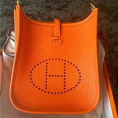 Hermes Mini Evelyn Tpm In Clemence Taurillion Mini Evelyne Hermes, Hermes 2424 Mini Bag, Hermes Evelyn Bag, Hermes Evelyne Mini Orange, Hermes Orange Bag, Hermes Handbags, Hermes Bags, Luxury Bags, Bag Lady