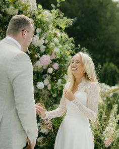 a man and woman standing next to each other in front of flowers