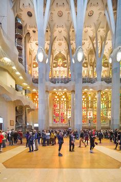 many people are standing in the middle of a large room with high ceilings and stained glass windows