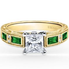 a princess cut engagement ring with emerald stones on the sides and an accent diamond in the middle