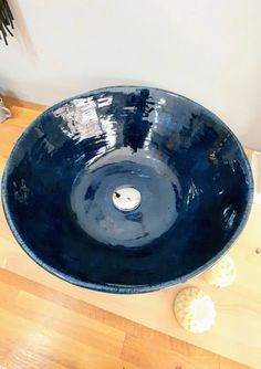 a large blue bowl sitting on top of a wooden table next to seashells