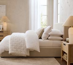 a bed with white linens and pillows in a neutral room next to a window