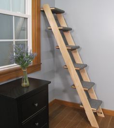 a wooden ladder leaning against the wall next to a vase with flowers