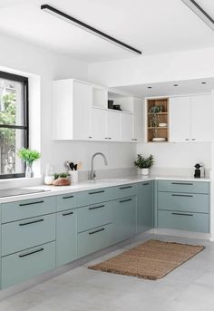 a kitchen with blue cabinets and white counter tops is pictured in this image, there is a rug on the floor next to the sink