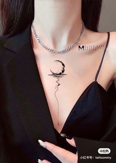 a woman wearing a black dress with a crescent moon tattoo on her chest and necklace