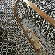 an overhead view of a stair case with black and white patterns on the wall behind it