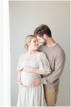 a pregnant couple cuddles and smiles at each other