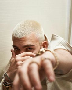 a man pointing at the camera with his finger in front of him and wearing bracelets around his neck