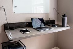 a laptop computer sitting on top of a wooden desk next to a phone and lamp