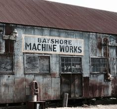 an old rusty building with the words bayshore machine works painted on it