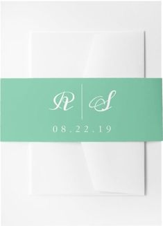 a white envelope with a green ribbon and two initials on it