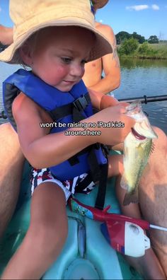 a young boy holding a fish while sitting in a boat