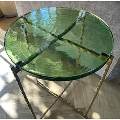 a green glass table sitting on top of a wooden floor