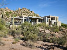 the desert house is surrounded by cactus and rocks