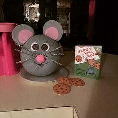 a gray mouse sitting on top of a table next to cookies