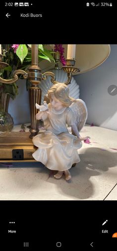 a little angel figurine sitting on top of a table next to a lamp