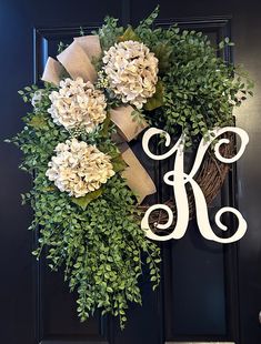 a wreath with the letter k on it is hanging on a black front door,