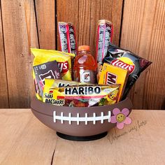 a football themed basket filled with candy, snacks and candies sits on a wooden table