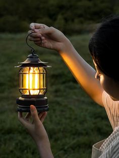 a woman holding a lantern in her hand with the light on it's side