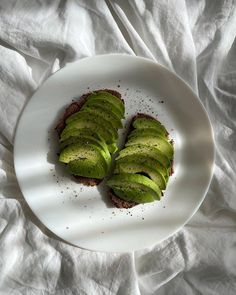 two pieces of bread with avocado slices on them sitting on a white plate