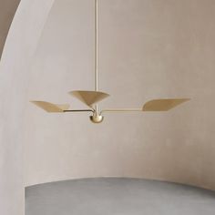 a ceiling lamp with three lights hanging from it's sides in an arch shaped room