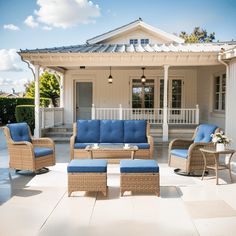 an outdoor living area with blue cushions and wicker furniture in front of a white house