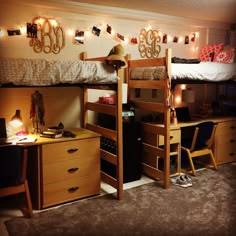 a bedroom with bunk beds, desks and lights on the wall above them is lit up by string lights