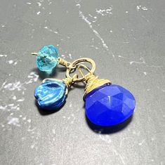 This TRIO gemstone pendant features of Royal Blue Chalcedony, Blue Keshi Pearl and Aquamarine Quartz ★ Stone measures      * Royal Blue Chal. 9x9 mm      * Keshi 6-8 mm      * Aqua Rondelle  6 mm ★ Jump ring size - 7mm ★ Total pendant - 1 inch Each stone is hand wrapped in the metal of your choice Sterling Silver, or 14k Gold Filled/14k Rose Gold Filled and attached to an open jump ring that fits over most clasps and standard chains.  Due to the nature of the stones, each piece may vary slightly Blue Faceted Pendant Jewelry, Faceted Blue Pendant Jewelry, Blue Faceted Briolette Jewelry, Blue Faceted Round Pendant Necklaces, Blue Faceted Round Pendant Necklace, Blue Briolette Wire Wrapped Necklaces, Blue Wire Wrapped Briolette Necklaces, Kesha, Keshi Pearls