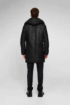 Men's Hooded Shearling Leather Coat In Black Wrap yourself in the luxurious warmth of this men's hooded shearling leather coat in sophisticated black. Expertly crafted from genuine sheepskin leather with a semi-aniline finish, this coat features a plush faux shearling inner shell. The stylish button closure, hooded collar, and open hem cuffs with shearling detail combine functionality with fashion. With two side pockets for convenience, this coat is the epitome of winter elegance and comfort. Ou Black Sheepskin Long Coat, Luxury Black Parka For Winter, Black Sheepskin Fur Coat For Cold Weather, Luxury Black Sheepskin Fur Coat, Luxury Black Winter Parka, Black Hooded Fur Coat With Detachable Hood, Luxury Hooded Fur Coat For Cold Weather, Winter Shearling Leather Jacket With Hood, Luxury Hooded Shearling Outerwear