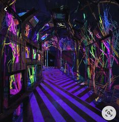 an art installation with neon lights and trees on the walls, along with black and white striped flooring