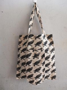 two bags hanging on a wall with birds printed on them, one is black and the other is white