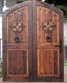 two wooden doors with metal handles on the outside of a house in front of a gate