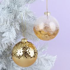 two gold and silver ornaments hanging from a white christmas tree