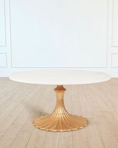 a round white table sitting on top of a hard wood floor next to a wall