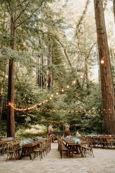 an outdoor dining area in the woods with tables and chairs set up for a party