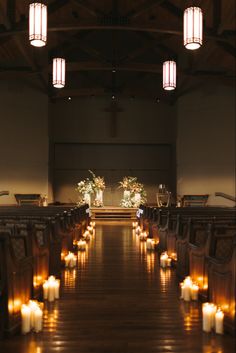 rows of lit candles line the aisle of an empty church