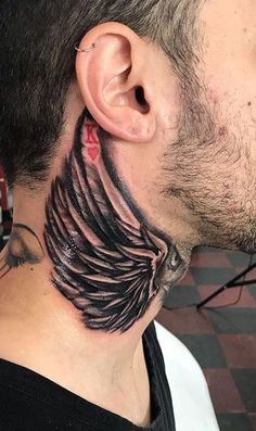 a man's neck tattoo with black feathers on it