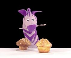 a purple zebra holding a spoon in front of some muffins