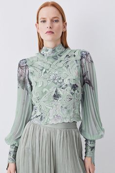 A Celebration Of The New Season, The By Lydia Spring '23: An Elegant Evolution Collection Showcases Style Escapism Through A Luxe Collection Of Designs That Accompany The Spring Season.Woven In A Soothing Sage Hue, This Blouse Makes An Elegant Addition To Your Occasionwear Collection. Intricate Applique Details Add Dimension To The Piece, Further Enhanced By An Illustrated Floral Print, Which Evokes A Feeling Of Optimism. The Blouson Sleeves Are Crafted From Sheer Fabric And Showcase A Pleated D Feminine Evening Top With Blouson Sleeves, Green Evening Tops For Spring, Fitted Blouson Sleeve Tops For Spring, Elegant Floral Print Party Tops, Feminine Spring Top With Blouson Sleeves, Feminine Spring Tops With Blouson Sleeves, Elegant Spring Blouse With Floral Embroidery, Chic Floral Embroidered Top For Evening, Chic Floral Embroidery Top For Evening