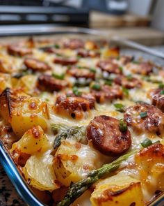 a casserole dish with potatoes, asparagus and sausage on it is ready to be eaten