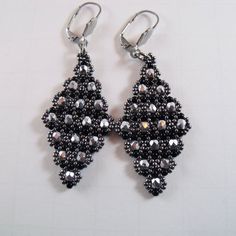 A pair of diamond shaped dangle and drop earrings. These beaded triangle earrings are woven with silver faceted and gray glass beads. Earrings hang from tarnish resistant stainless steel lever back ear wire. Earrings measure:  Total length is 2.50" inches ( 6.35 cm ) from ear hole to bottom of beads. The widest part of the earring is 1.00" inch ( 2.54 cm ) across. https://www.etsy.com/shop/FMGuyDesigns Elegant Gray Metal Earrings, Silver Beaded Earrings For Evening, Gray Beaded Dangle Earrings, Silver Triangle Earrings For Party, Triangle Silver Jewelry For Party, Silver Triangle Party Earrings, Handmade Gray Beaded Dangle Earrings, Silver Chandelier Earrings With Faceted Beads, Silver Teardrop Earrings With Faceted Beads