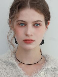 a woman with blue eyes wearing a necklace