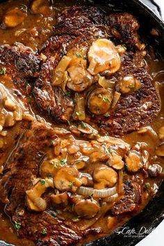 two steaks covered in mushroom gravy in a cast iron skillet