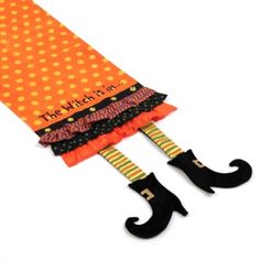 an orange umbrella with black legs and polka dots on it, has the words the witch is in