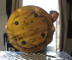 a man holding up a large wooden board on top of a checkered table cloth