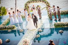 a bride and groom walking down the aisle to their wedding ceremony in front of an outdoor pool