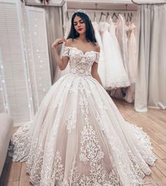 a woman standing in front of a mirror wearing a wedding dress with flowers on it